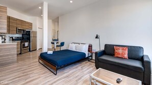 A modern hotel room with a bed, a sofa, a small table, and a kitchenette. - Chicago Third Floor Studio by 747 Lofts (Chicago)