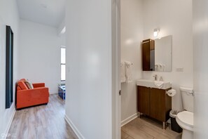Bathroom features a clean, minimalist design with a vanity, mirror, and toilet.