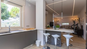 Eine moderne Küche mit großem Fenster, integriertem Spülbecken und einer Bar mit Hockern.