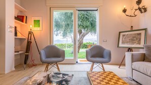 Ein Wohnzimmer mit zwei Sesseln, einem Sofa, einem Couchtisch und einem Bücherregal.