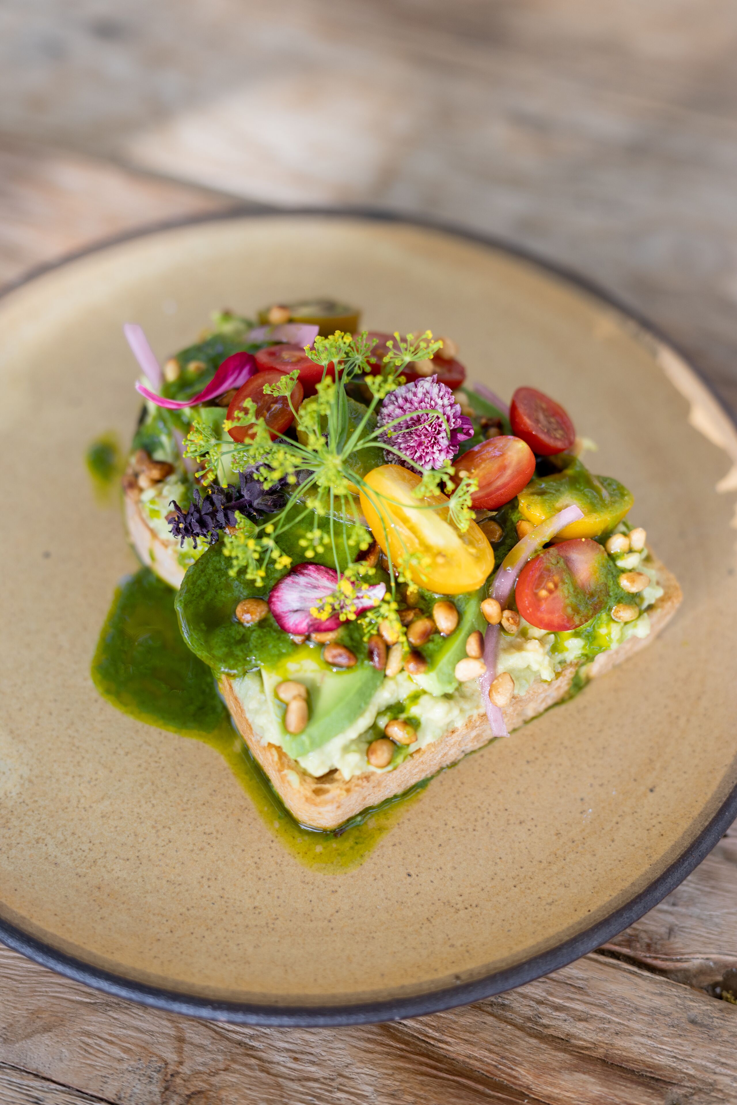 A square plate with a green salad on a beige plate.