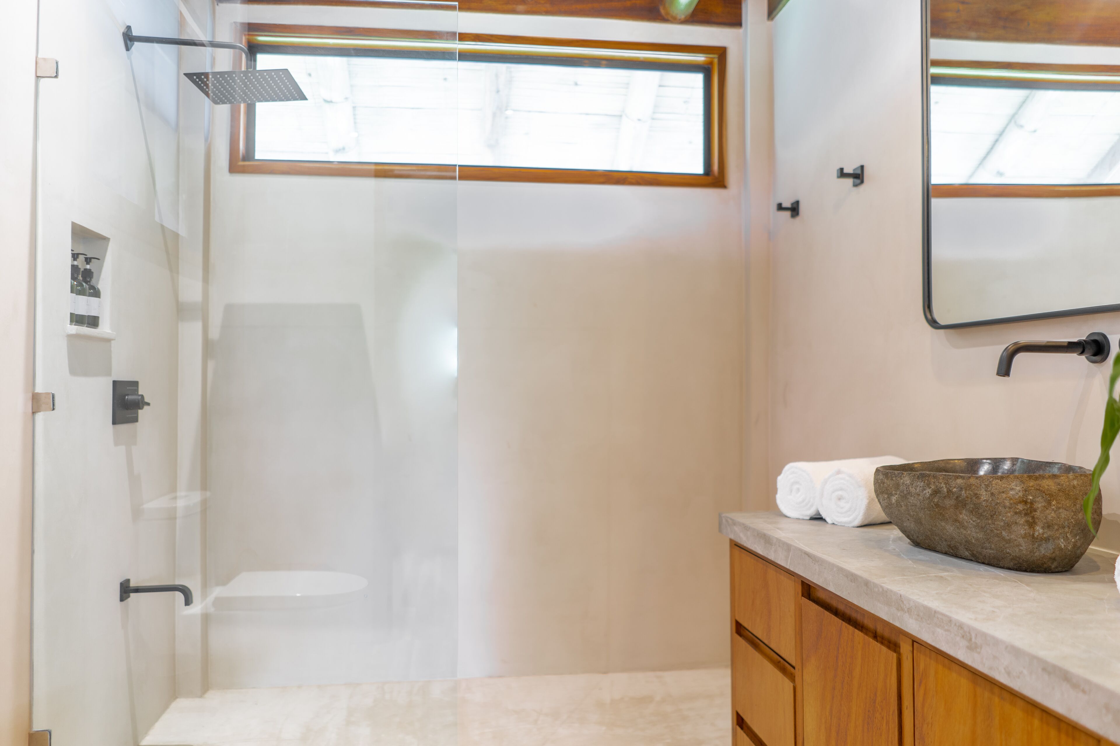 A modern bathroom with a glass-enclosed shower, a wooden vanity, and a large mirror.