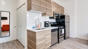 A modern kitchen with wooden cabinets, a stainless steel refrigerator, a built-in oven, and a microwave. - River West, Third Floor Chicago by 747 Lofts (Chicago)