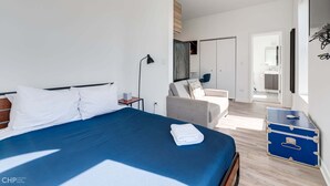 A modern hotel room with a large bed, a seating area, and a suitcase. - River West, Third Floor Chicago by 747 Lofts (Chicago)