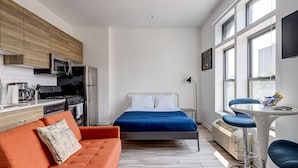 A compact bedroom with a bed, a small kitchenette, a sofa, and a dining table. - River West, Third Floor Chicago by 747 Lofts (Chicago)