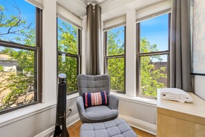 A room with a window seat, a standing heater, and a towel on a wooden table.