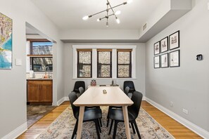 A dining area with a table, chairs, and a ceiling light fixture.