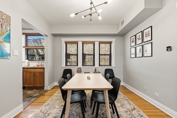 A dining area with a table, chairs, and a ceiling light fixture.