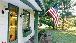 Ett hus med en grön dörr, ett fönster med ett rutmönster och en amerikansk flagga.