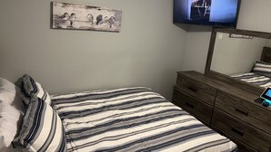 A bedroom with a bed, a dresser, a television mounted on the wall, and a painting on the wall. - Beautiful Home (Riverdale)