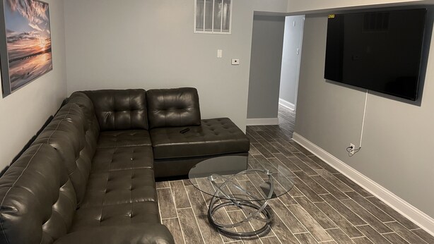 A modern living room with a sectional sofa, a flat-screen TV, and a glass coffee table. - Beautiful Home (Riverdale)