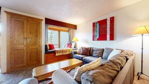 Ett vardagsrum med en trägarderob, en soffa, ett soffbord och en lampa.