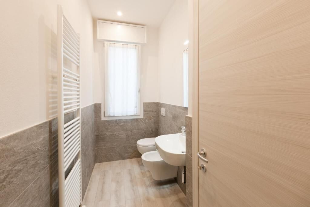 Een kleine badkamer met toilet, wastafel en raam.