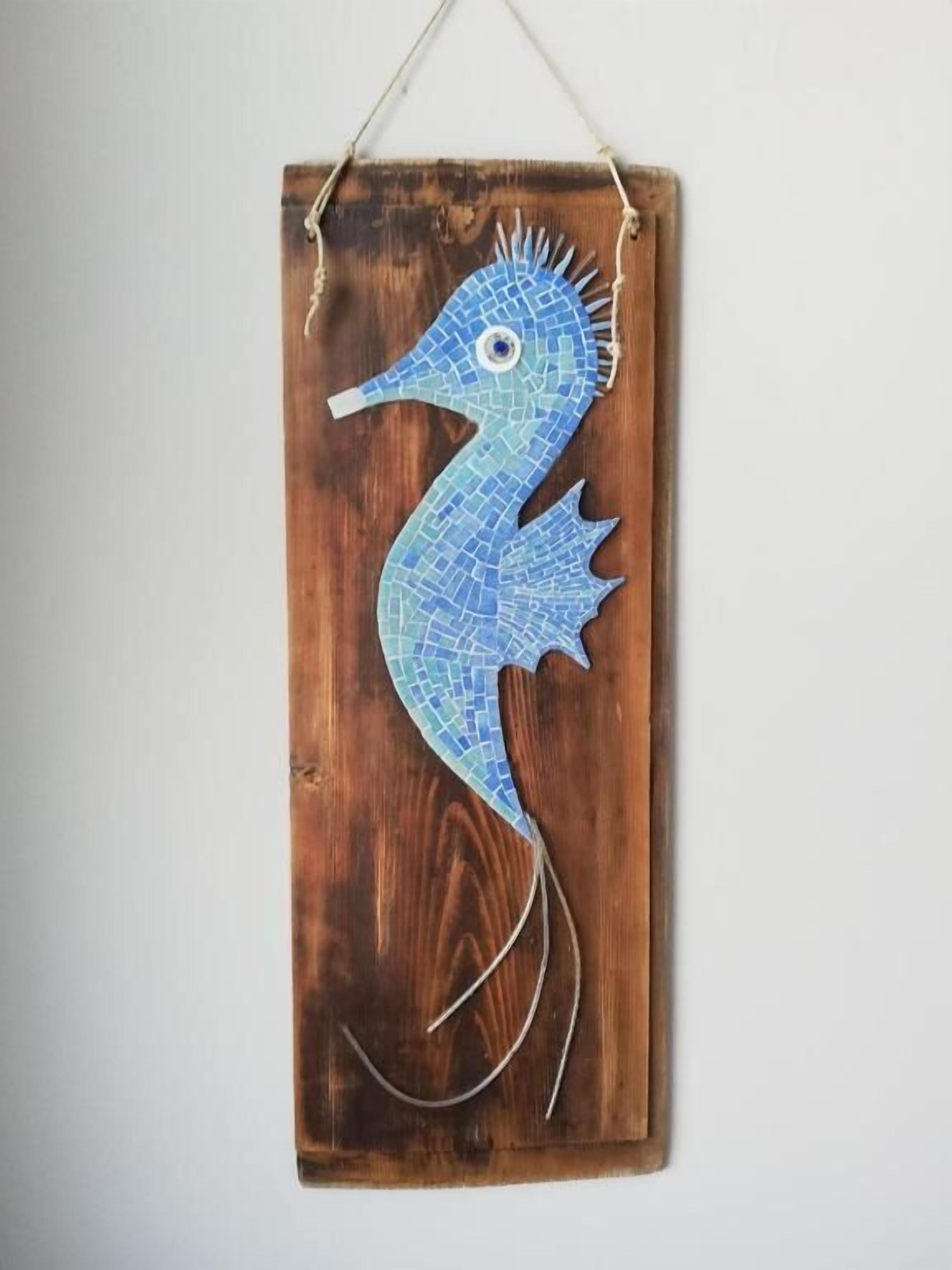 Eine hölzerne Seepferdchen-Dekoration mit blauem Mosaikmuster.
