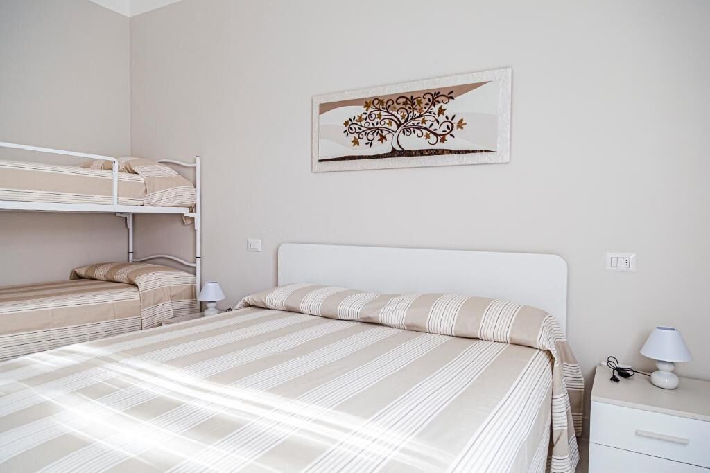 A single bed with a striped bedspread, a nightstand with a lamp, and a wall-mounted picture.