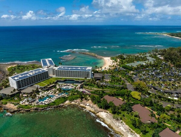 A resort with a large building, a pool, and a view of the ocean.