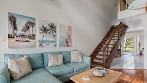Un salon avec un canapé de couleur turquoise, une table basse en bois et un escalier menant à un niveau supérieur.