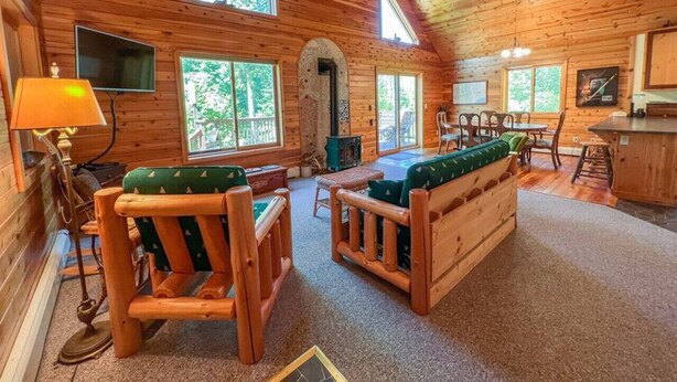 Ein gemütliches Blockhaus-Interieur mit Holzwänden, Kamin und Essbereich.