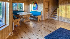 Puinen mökki, jonka sisätiloissa on puulattia, pöytä, sininen sohva ja värikäs abstrakti maalaus seinällä.