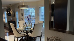 A modern dining area with a glass table, white chairs, and a decorative centerpiece. - Mai Villa-Hampton - Where good times happen! (Hampton)