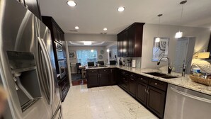 A modern kitchen with stainless steel appliances, dark cabinetry, and a marble floor. - Mai Villa-Hampton - Where good times happen! (Hampton)