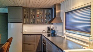 A compact kitchen with dark cabinets, a built-in oven, and a window with blinds.