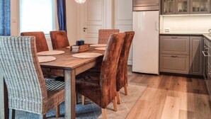 A dining area with a wooden table, six chairs, and a kitchen with cabinets and a refrigerator.