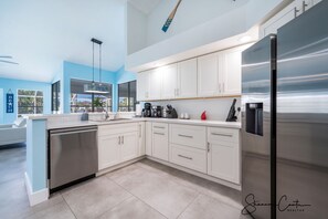 A modern kitchen with white cabinets, stainless steel appliances, and a blue accent wall.