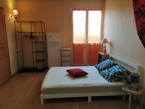 Un dormitorio con cama, armario, escritorio, lámpara y ventana con cortinas.