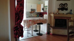 Una cocina con comedor, chimenea y una cortina roja.