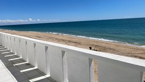 Ein Balkon mit Blick auf einen Sandstrand und das Meer.