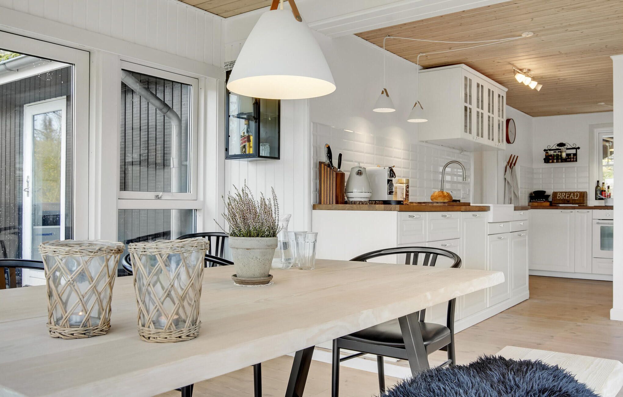 A modern kitchen with white cabinets, a wooden countertop, and a dining area with a table and chairs.
