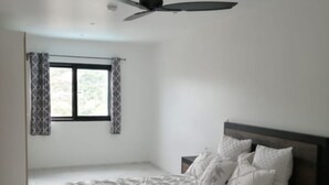 A bedroom with a bed, a ceiling fan, a window with curtains, and a nightstand. - Spectacular view of the Caribbean Sea (Sint Maarten)