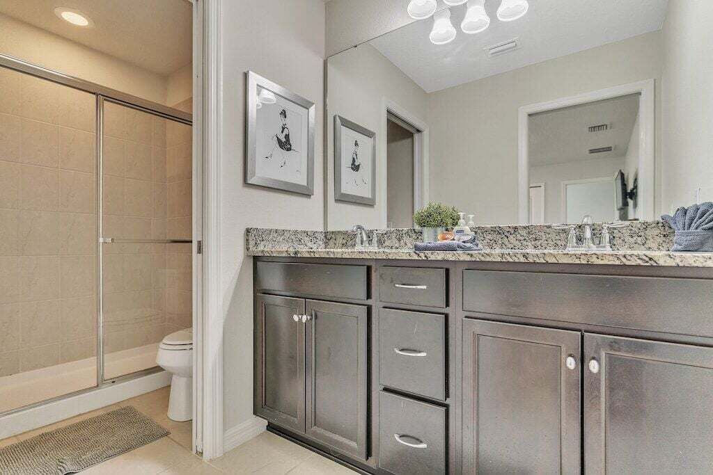 Un baño moderno con ducha, tocador y un espejo grande.