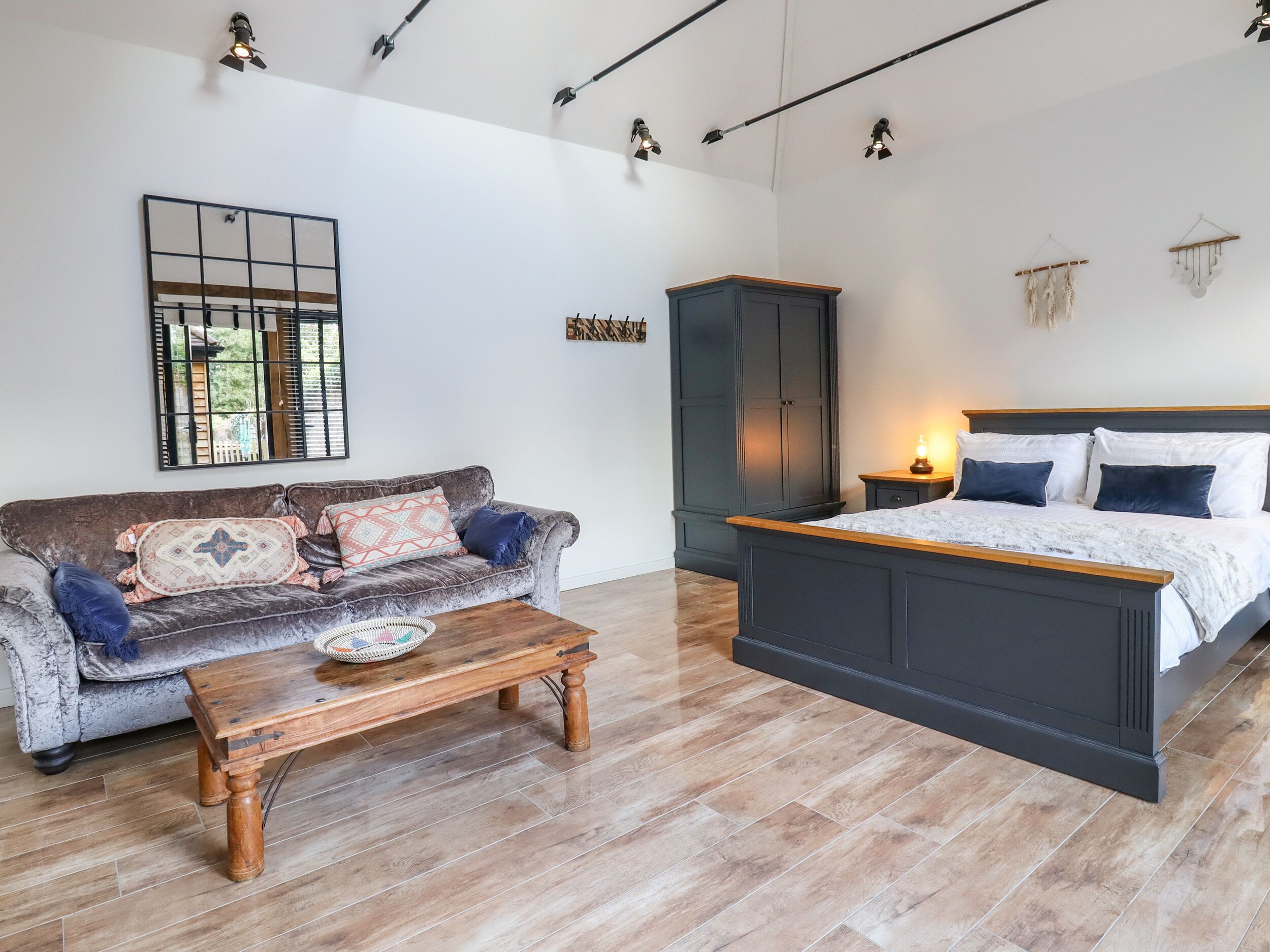 A bedroom with a bed, a sofa, a wooden coffee table, and a wardrobe.