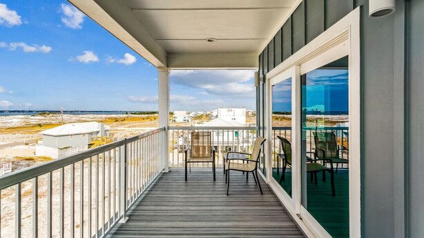 Un balcón techado con vista a la playa y edificios a lo lejos.