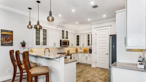 Una cocina moderna con armarios blancos, una isla central e iluminación colgante.