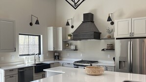 A modern kitchen with a large island, stainless steel appliances, and pendant lighting. - Secluded, Cozy Shouse near the Lake!  (Roosevelt)