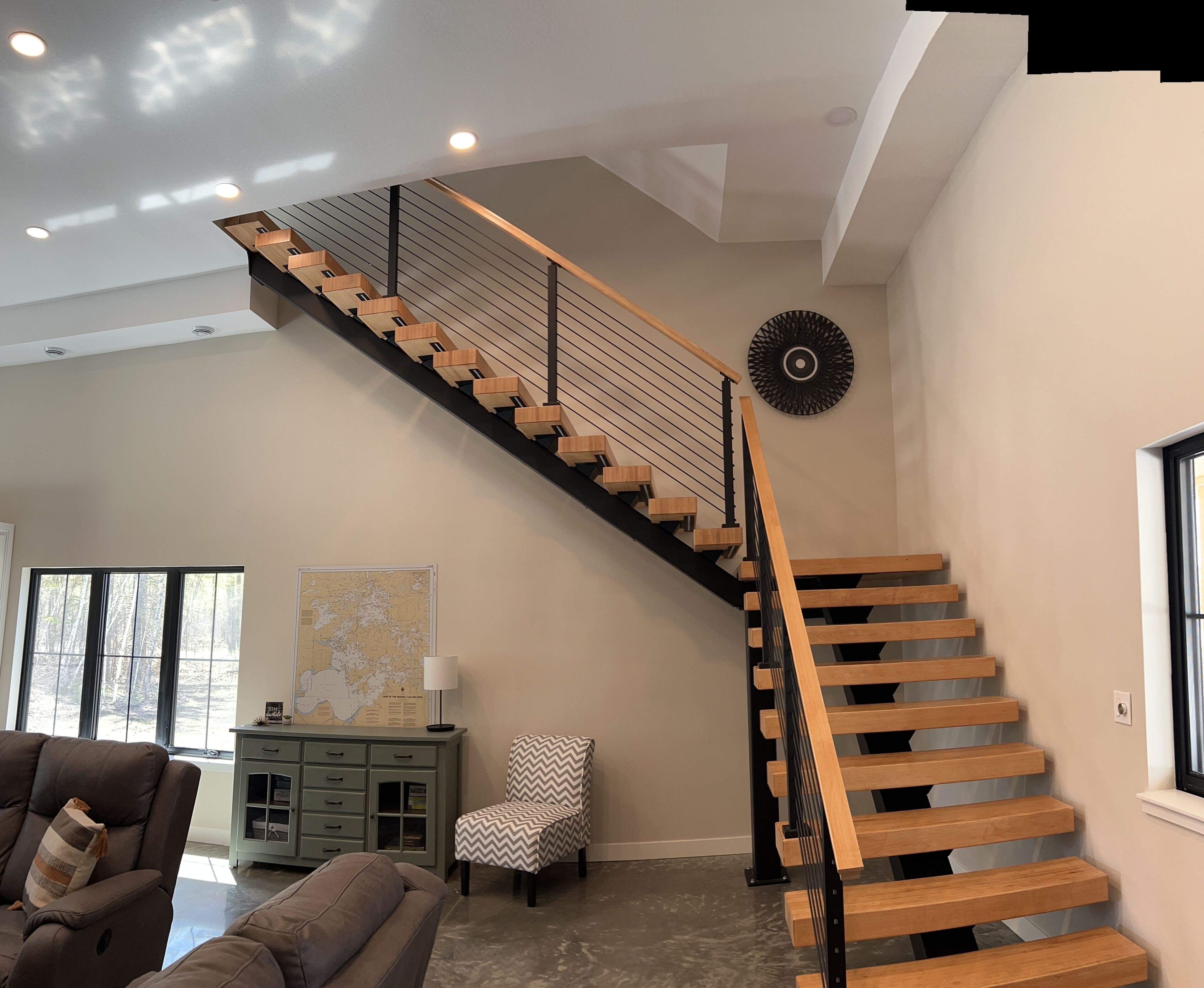 Ein modernes Interieur mit einer Holztreppe, einer Karte an der Wand und einer Sitzecke mit einer Lampe.