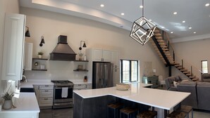 A modern kitchen with white cabinetry, a central island, and a built-in stove. - Secluded, Cozy Shouse near the Lake!  (Roosevelt)