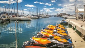 Uma marina com vários barcos atracados e jet skis alinhados no cais.