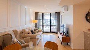 Ein stilvolles Wohnzimmer mit einer Sofagarnitur, einem Glastisch und einer TV-Konsole.