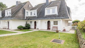 A two-story house with a white exterior, multiple chimneys, and a well-maintained lawn.