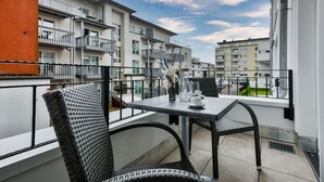 A balcony with a table and chairs, overlooking a residential area with multiple apartment buildings.