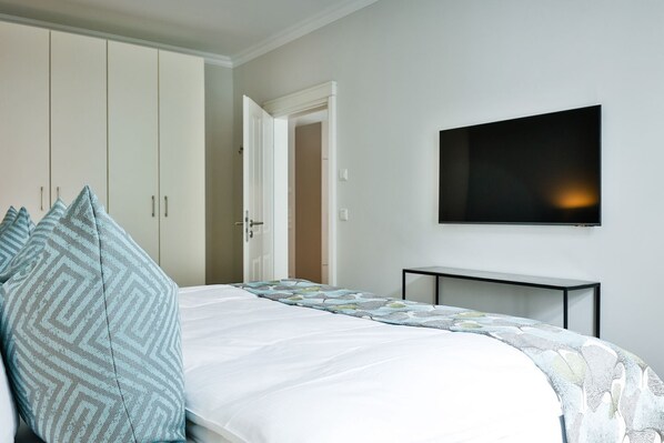 A bedroom with a bed, pillows, a TV, and a wardrobe.