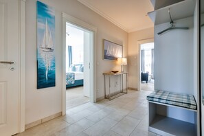 A hallway with a bed, a console table with a lamp, and a hanging coat rack.