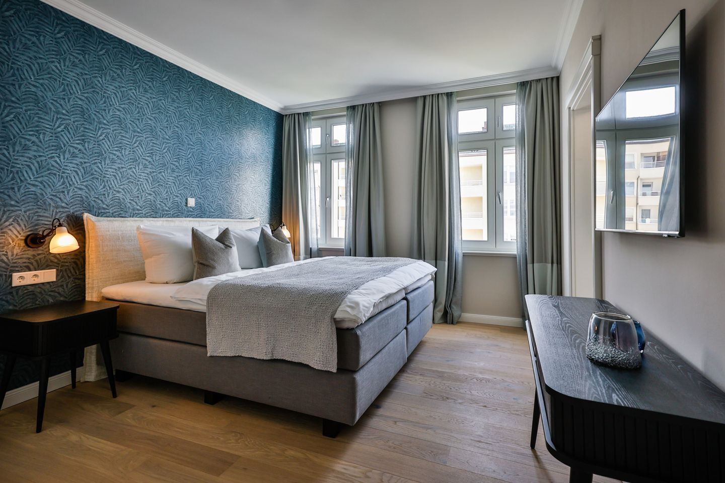 Een slaapkamer met een bed, nachtkastjes, een bureau en een raam met gordijnen.