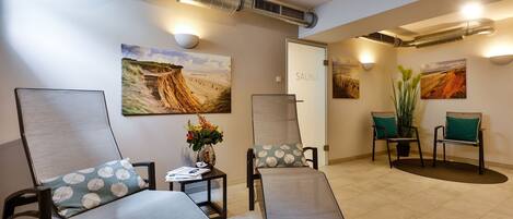 A spa room with reclining chairs, a massage table, and artwork on the walls.