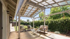 A covered patio with a pergola, outdoor seating, and a view of a garden. - King Beds! - Clean and Spacious 5 bed 3 bath home (Citrus Heights)