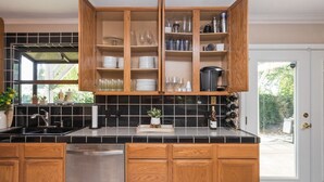 A kitchen with wooden cabinets, black tiled backsplash, and a stainless steel sink. - King Beds! - Clean and Spacious 5 bed 3 bath home (Citrus Heights)